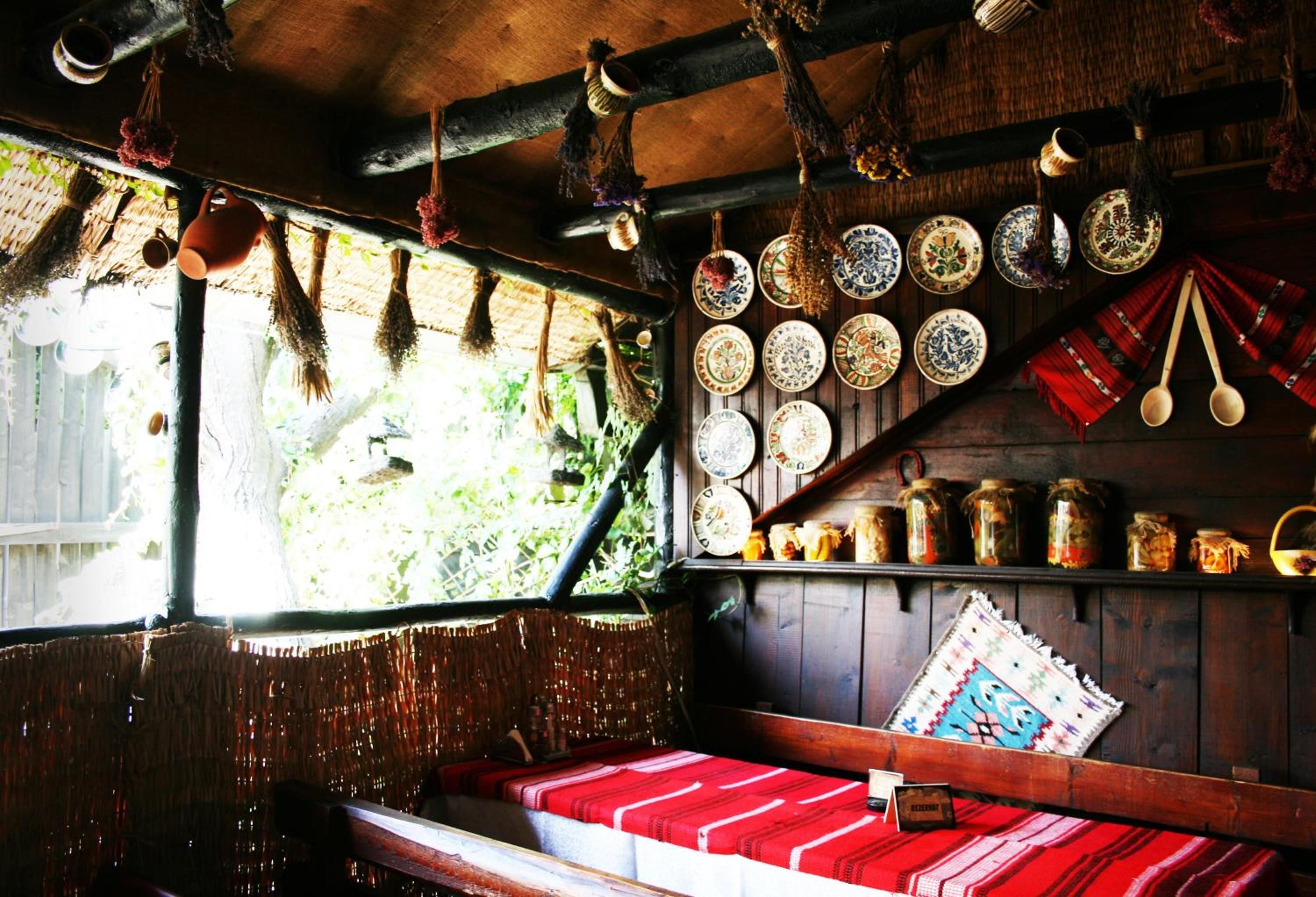 Un interior rústico con un banco de madera, adornos colgantes y una pared llena de platos y frascos.