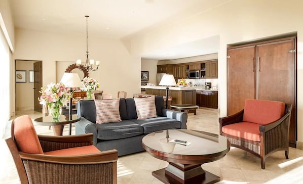 A spacious living area with a sofa, chairs, a coffee table, and a kitchen in the background. - The Reserve At Diamante Los Cabos (Cabo San Lucas)