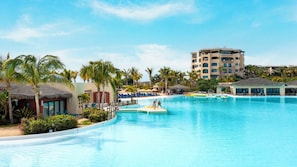 Un resort con una gran piscina, palmeras y un edificio de varios pisos.