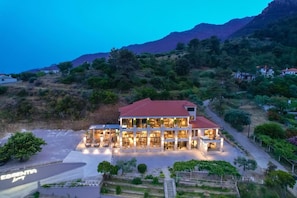 A two-story building with a red roof, surrounded by greenery and hills. - Essentia Luxury (Thasos)