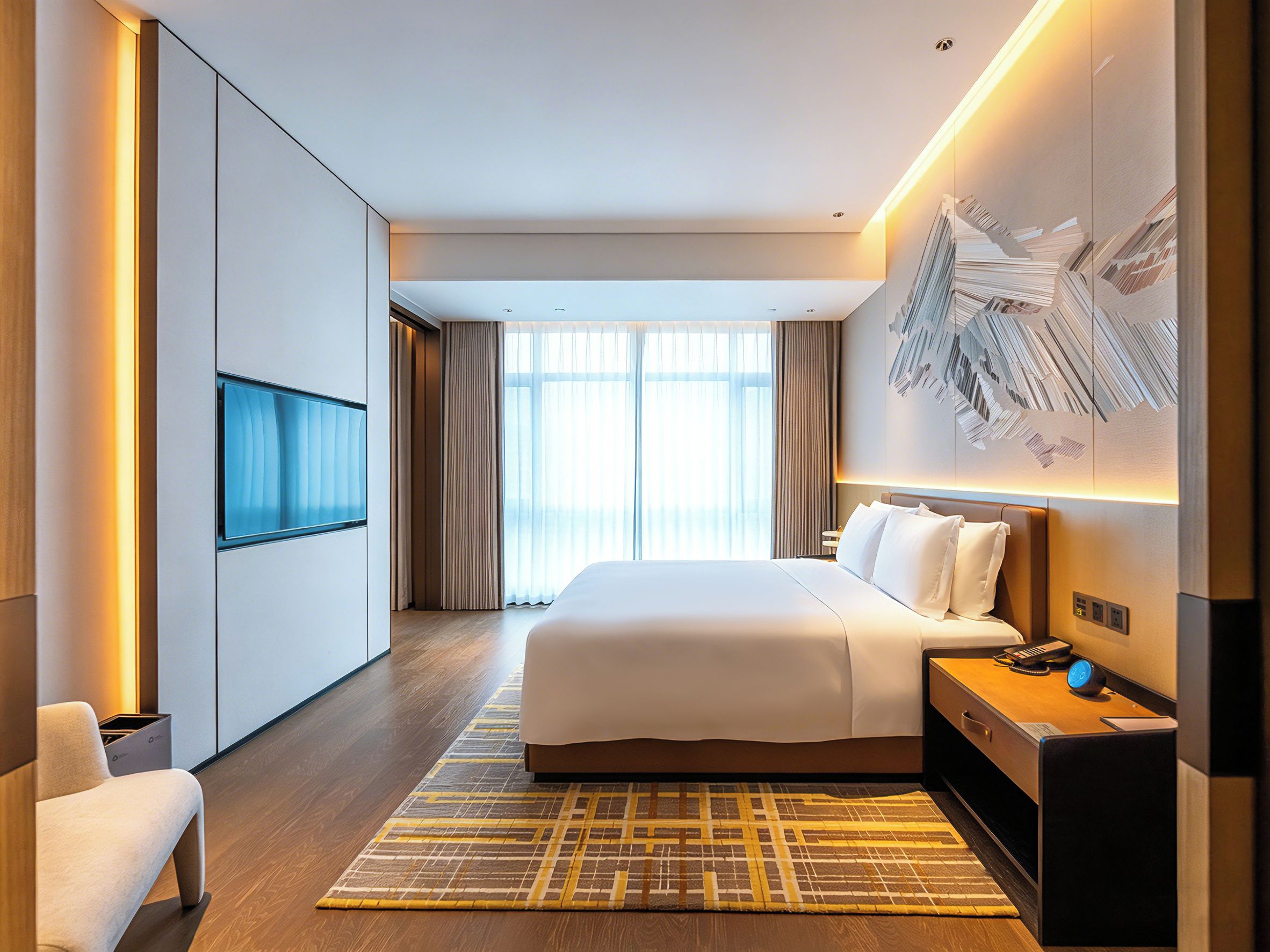 Quarto de hotel moderno com uma cama grande, televisão de tela plana, escrivaninha com cadeira e uma janela ampla com cortinas.