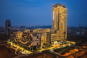 A high-rise hotel with multiple floors, a well-lit entrance, and a parking area. - Grand Skylight Hotel Wuhan Optics Valley (Wuhan)