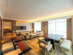A modern hotel room with a sofa, chairs, a dining table, a TV, and a large window with curtains. - Grand Skylight Hotel Wuhan Optics Valley (Wuhan)