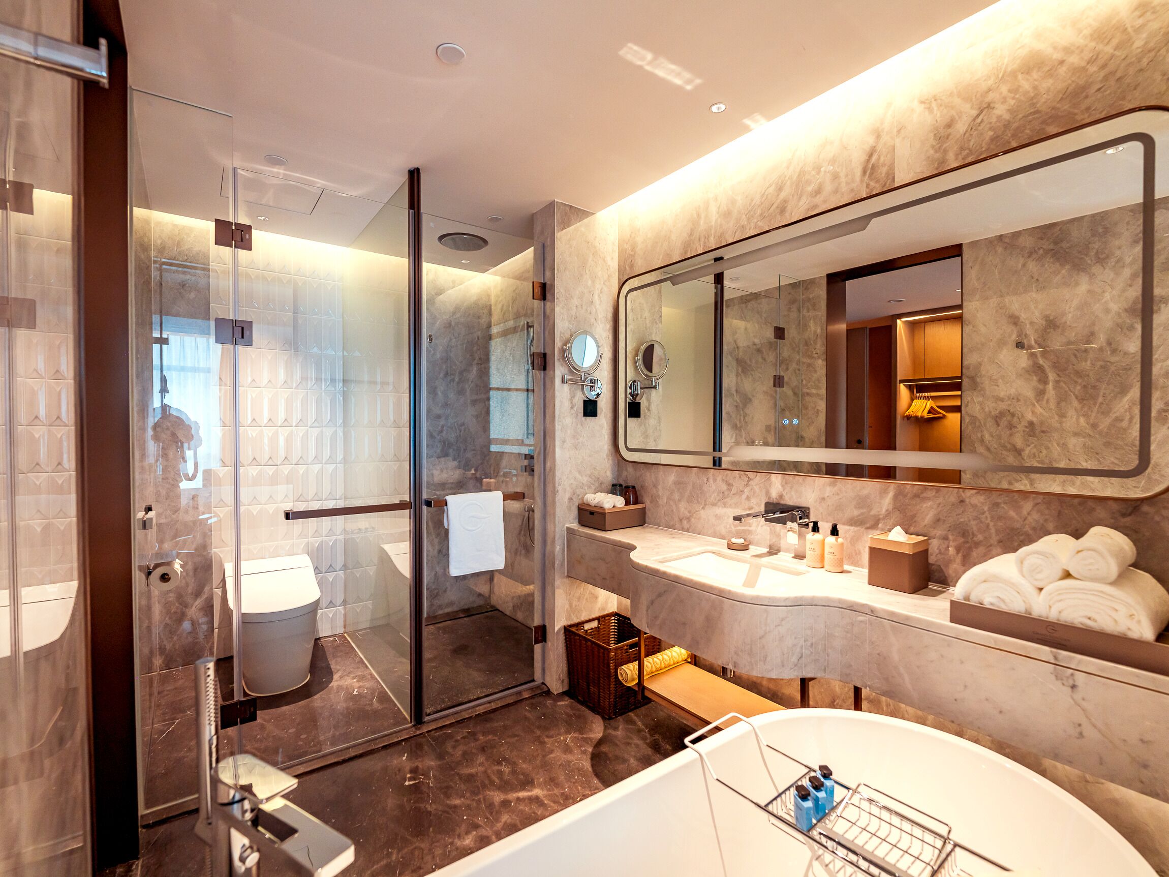 A modern bathroom with a glass shower enclosure, a large mirror, and a bathtub.