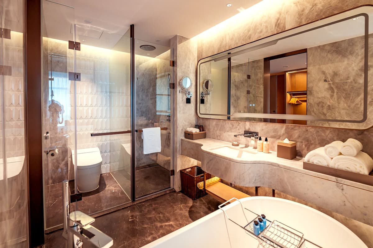 Un baño moderno con cabina de ducha de vidrio, un espejo grande y una bañera.