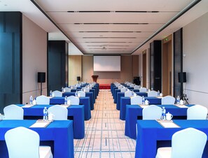 A conference room with rows of tables and chairs, a podium, and a large screen at the front. - Grand Skylight Hotel Wuhan Optics Valley (Wuhan)