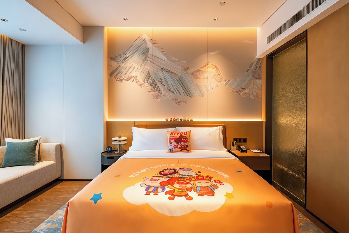 Habitación de hotel con cama, mesita de noche, sofá y una obra de arte grande en la pared.