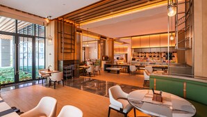 A modern restaurant with a bar area, seating arrangements, and a kitchen visible in the background. - Grand Skylight Hotel Wuhan Optics Valley (Wuhan)