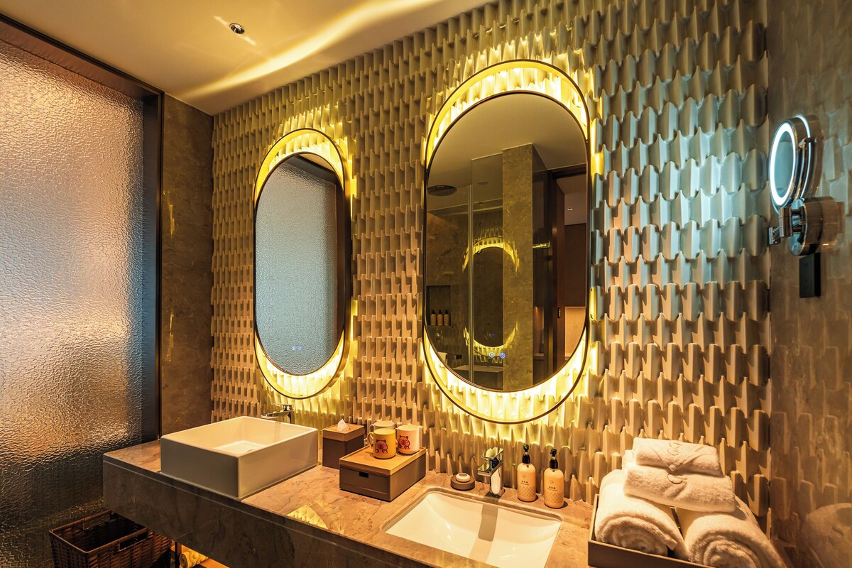 A modern bathroom with two sinks, a large mirror, and a towel rack.