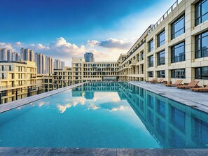 A modern hotel with a rooftop infinity pool, reflecting the surrounding buildings and sky. - Grand Skylight Hotel Wuhan Optics Valley (Wuhan)