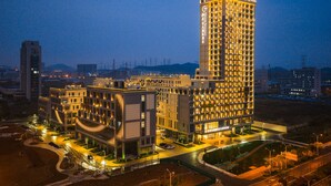 A high-rise hotel with multiple floors, a well-lit entrance, and a parking area. - Grand Skylight Hotel Wuhan Optics Valley (Wuhan)