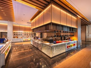 Una cocina moderna con una isla central, iluminación colgante y piso pulido.