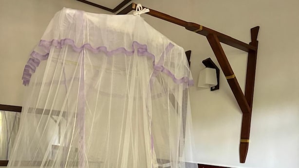 A bed with a white canopy and a wooden headboard. - Dambulla Hills Resort (Dambulla)