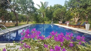A swimming pool with a clear blue water surface, surrounded by lush greenery and trees. - Dambulla Hills Resort (Dambulla)