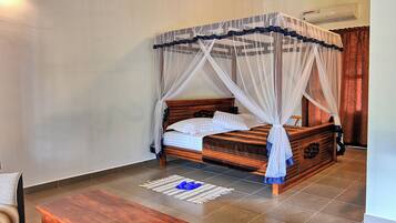 A bedroom with a wooden bed, a canopy, a wooden table, and a chair.