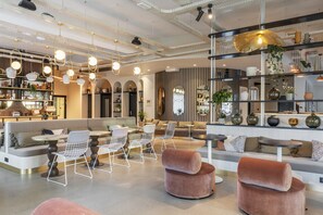 A modern interior with seating areas, pendant lighting, and decorative shelves. - Hotel-spa L'essenciel - Château Des Pères (Piré-Chancé)