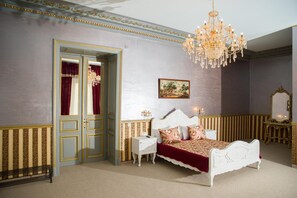 Un dormitorio con una cama grande, una araña, un cuadro y un espejo.