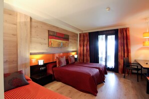 A hotel room with a wooden headboard, two beds with red bedding, a desk, and a chair. - Dolcet L Hotel (Alàs i Cerc)