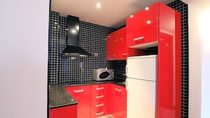 A modern kitchen with red cabinets, a black tiled backsplash, and a white refrigerator. - Dolcet L Hotel (Alàs i Cerc)