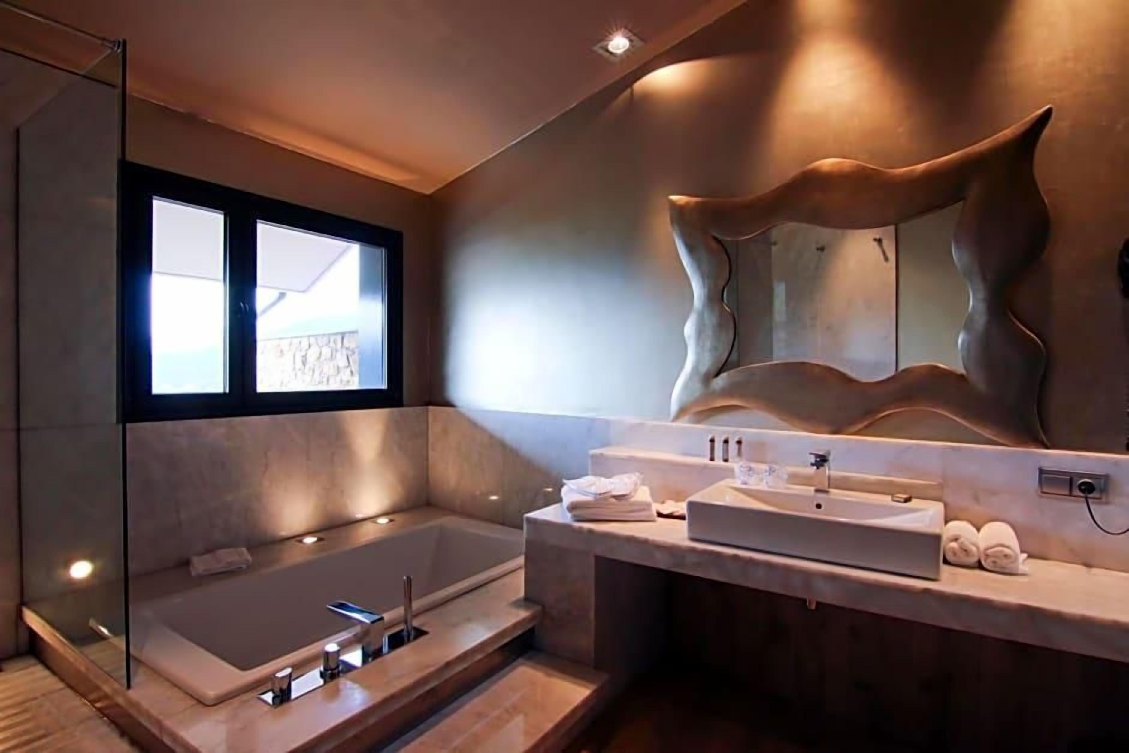 A modern bathroom with a large bathtub, a vanity with a mirror, and a view of the outdoors.