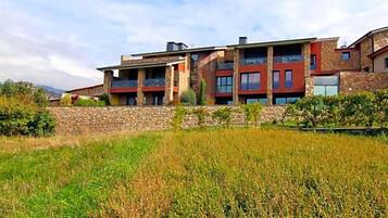 A modern multi-story building with a stone facade, large windows, and a flat roof.