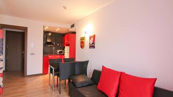A compact living space with a kitchenette, a dining area, and a seating area with a sofa and chairs.