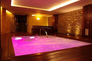 A spa area with a hot tub, wooden flooring, stone walls, and a staircase. - Dolcet L Hotel (Alàs i Cerc)