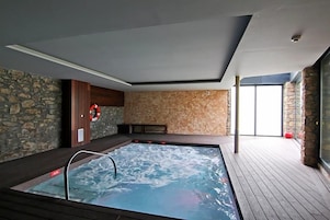 Un área de spa con un jacuzzi, paredes de piedra y una terraza de madera.