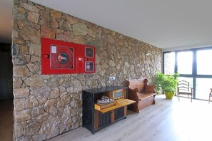 Un muro de piedra con una parrilla integrada, un banco de madera y una planta en maceta.