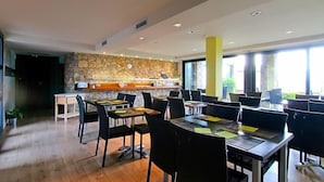 A restaurant with a stone wall, wooden tables, and chairs. - Dolcet L Hotel (Alàs i Cerc)