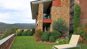 A modern house with a stone facade, a balcony, and a well-maintained lawn. - Dolcet L Hotel (Alàs i Cerc)