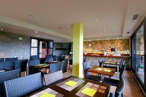 A restaurant with high tables and chairs, a stone wall, and a bar area. - Dolcet L Hotel (Alàs i Cerc)