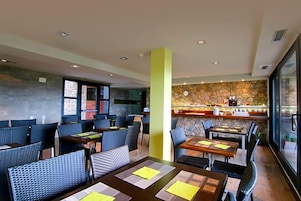 Un restaurante con mesas y sillas altas, una pared de piedra y una zona de bar.