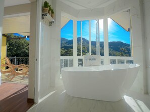 Ein modernes Badezimmer mit einer freistehenden Badewanne, großen Fenstern und Blick auf eine Berglandschaft.