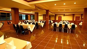 Un gran salón de banquetes con varias mesas redondas, sillas y un suelo pulido.