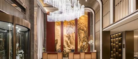 A modern lobby with a reception desk, a large abstract light installation, and a mural on the wall.