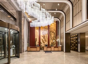 A modern lobby with a reception desk, a large abstract light installation, and a mural on the wall.