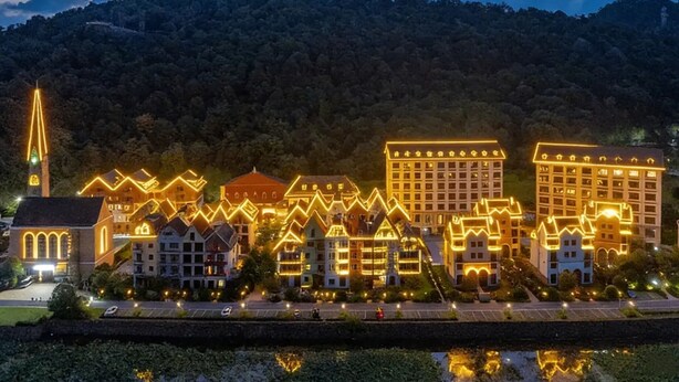 Un hotel con varias construcciones, una iglesia y el monte de fondo.