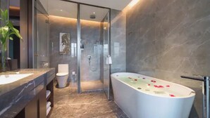 Un baño moderno con cabina de ducha de vidrio, una bañera independiente y suelo de mármol.
