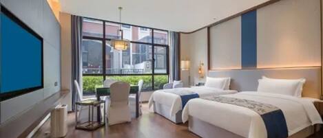 Una habitación de hotel con dos camas, un escritorio y un ventanal amplio.