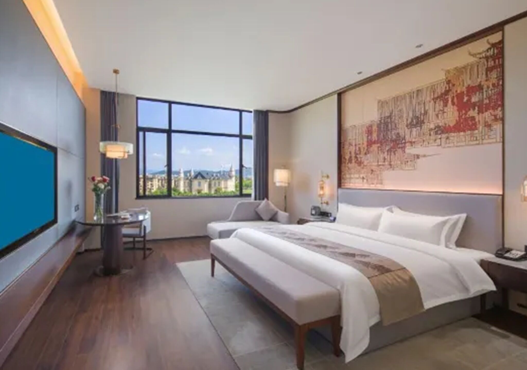 Une chambre d’hôtel avec un grand lit, un bureau, une chaise, une vue sur la ville et une grande œuvre d’art accrochée au mur.
