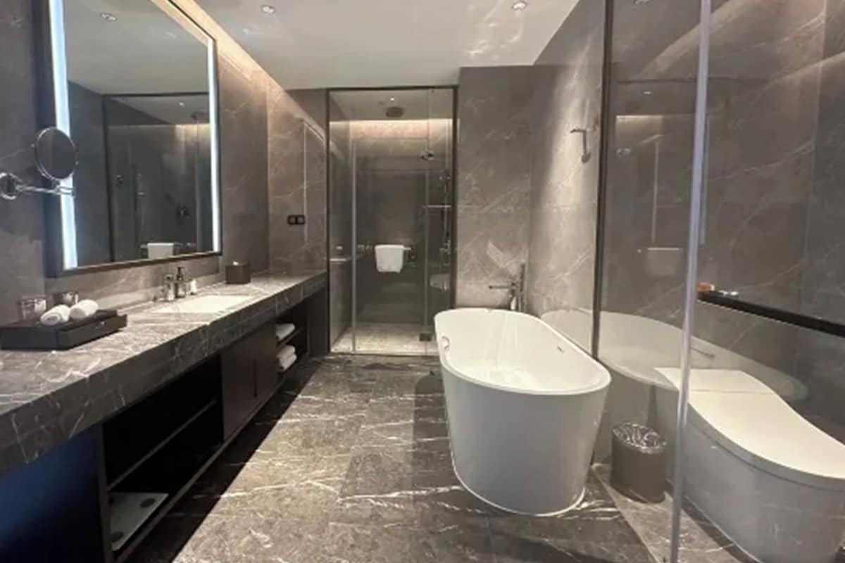 A modern bathroom with a freestanding bathtub, a glass-enclosed shower, and a large mirror.