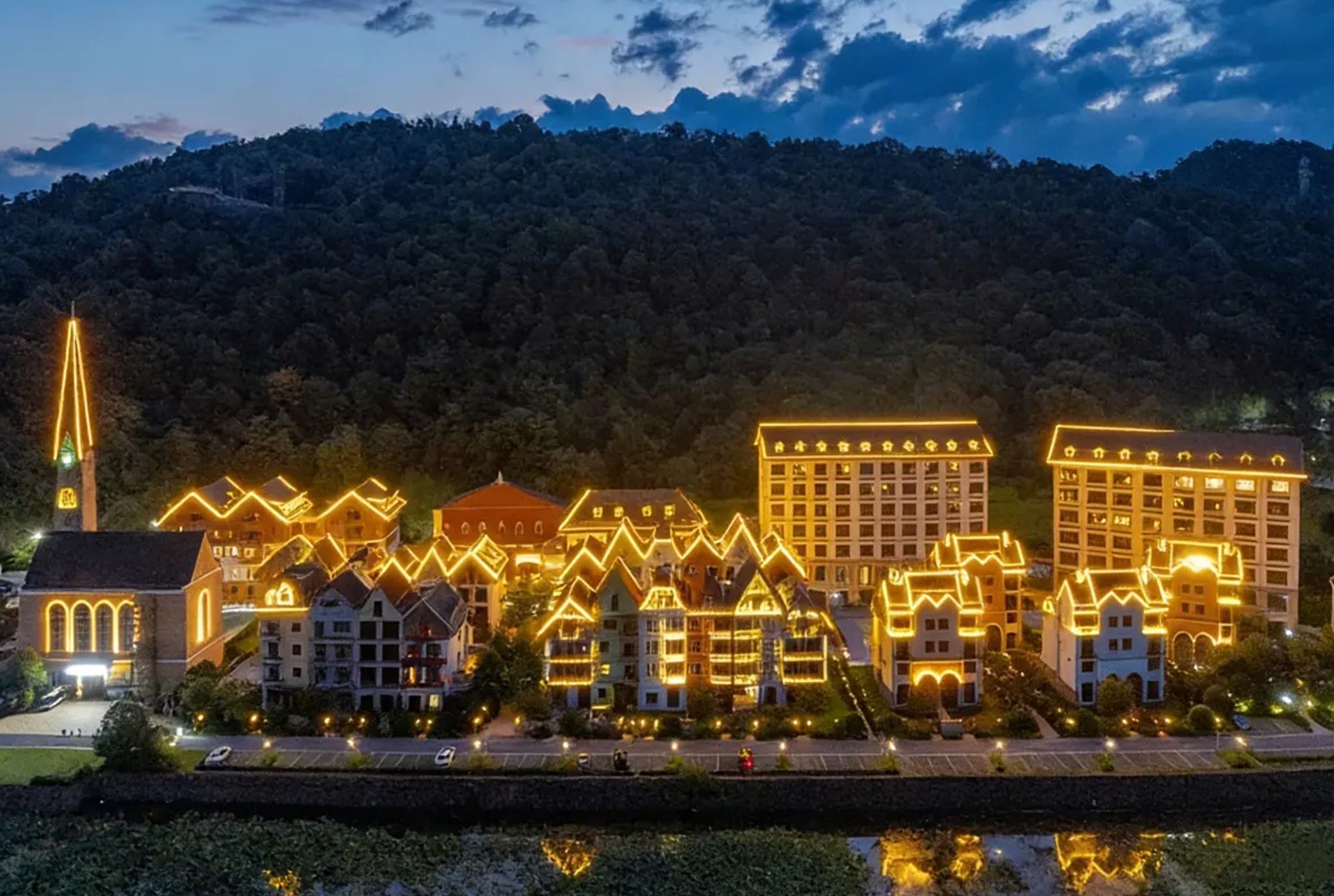 Un hotel con varias construcciones, una iglesia y el monte de fondo.
