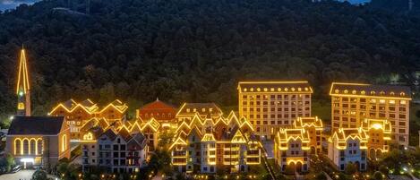 Un hotel con varias construcciones, una iglesia y el monte de fondo.