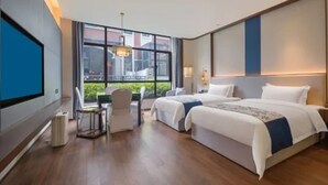 Una habitación de hotel con dos camas, un escritorio y un ventanal amplio.
