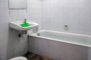 Une salle de bain avec un lavabo blanc, un receveur de douche vert, une baignoire blanche et des toilettes blanches.