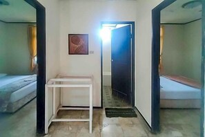 Una habitación con una cama, un escritorio blanco, una puerta y un cuadro colgado en la pared.