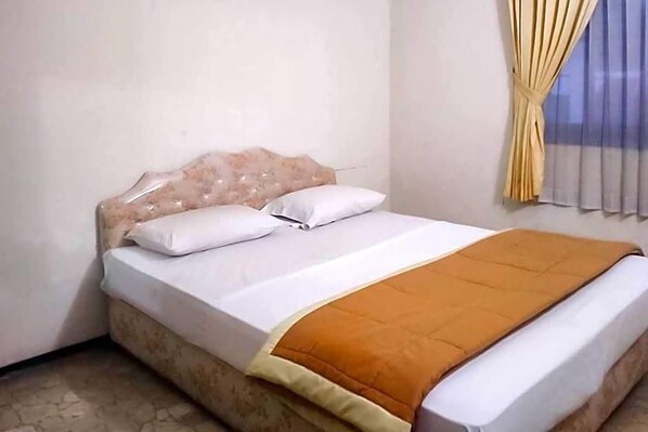 Una cama con cabecera, dos almohadas y una manta.
