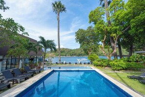 A swimming pool with lounge chairs, surrounded by greenery and a view of the sea. - Casalay Boutique Villas & Dive (Puerto Galera)