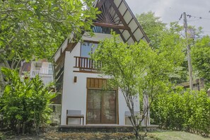 Ein zweigeschossiges Haus mit einem Balkon, großen Fenstern und einem Garten.